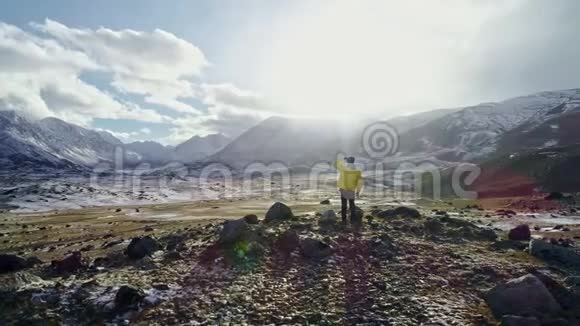 年轻的徒步旅行者伸出双臂成功地在日落时在雪山山脉空中飞行史诗般的胜利视频的预览图