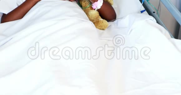 戴着氧气罩和泰迪熊休息的生病女孩视频的预览图
