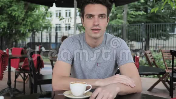 微笑的年轻人坐在咖啡馆的露台上视频的预览图