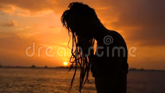 头发湿漉漉的女孩穿着比基尼在日落海滩上摆姿势视频的预览图