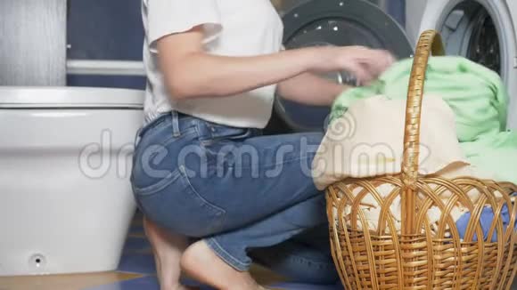 特写镜头不可辨认的女人把洗衣篮里的布放在洗衣机里视频的预览图