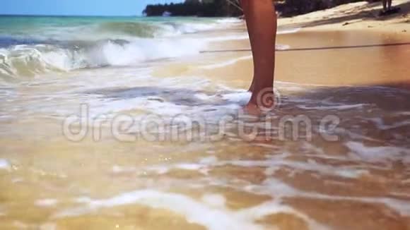 男人的双腿光着脚站在沙质海岸上海水缓慢地溅起波浪关闭1920x1080视频的预览图