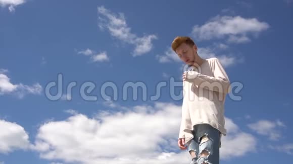 一个留着胡子的年轻帅哥在天空的背景下对着镜头摆姿势视频的预览图