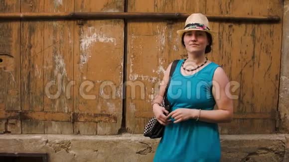 戴帽子的女人在旧墙的背景上摆姿势视频的预览图