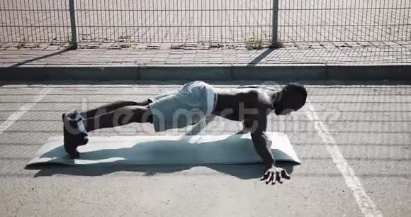 街头锻炼运动的非裔美国人在户外做俯卧撑和旋转运动一个黑人在玩视频的预览图