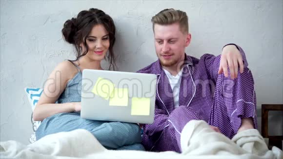 年轻夫妇一起看系列节目在床上聊天视频的预览图