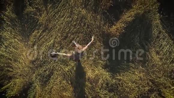 空中飞行迷人的女孩正在草地上旋转拿着一顶草帽从上面看视频的预览图
