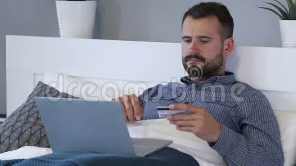 床上男人在笔记本电脑上购物付款视频的预览图