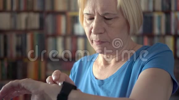 现代高级女性在家使用智能手表浏览阅读背景书架视频的预览图