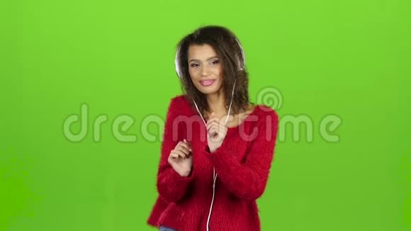 女性带着耳机绿色屏幕跳舞微笑慢动作视频的预览图