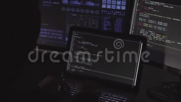 电脑黑客在黑暗的房间里用电脑和笔记本电脑写代码视频的预览图