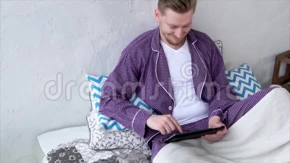 有笔记本电脑的人坐在床上与社交网络中的朋友交流视频的预览图