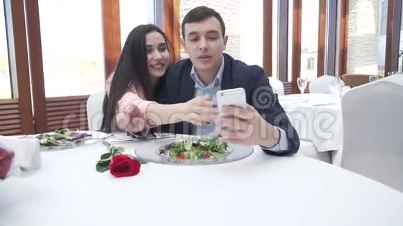 爱的幸福夫妻在餐厅通过iPhone慢动作的股票镜头在Instagram上自拍视频的预览图