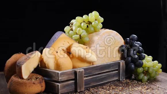 一套坚硬的奶酪漂亮地放在用葡萄装饰的木箱里在构图上缓慢下降视频的预览图