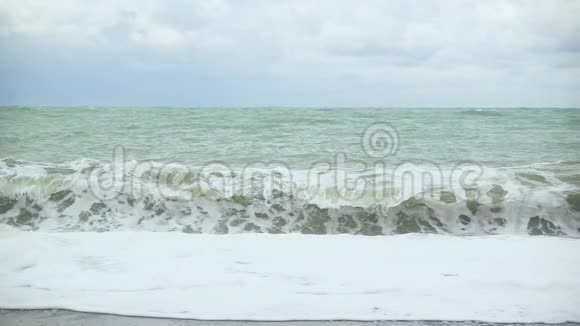 海浪中的泡沫卷起一片鹅卵石滩视频的预览图
