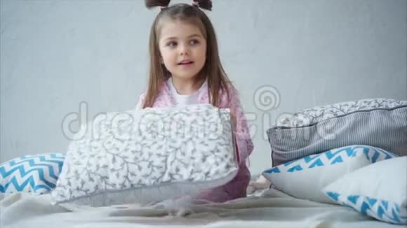 可爱的小女孩穿着粉红色睡衣在床上醒来快乐的孩子视频的预览图