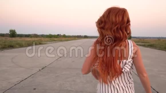 快乐的红发女人带着飞扬的头发在路上奔跑视频的预览图