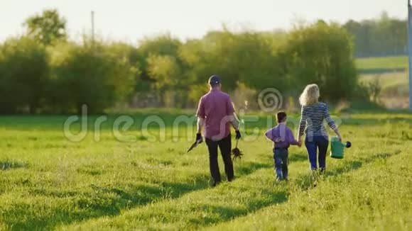 一对农民正沿着一条风景如画的乡村道路行走带着他们的小儿子去种树带一棵视频的预览图