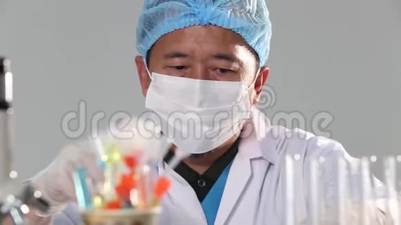 亚洲男子医生带口罩橡胶头盔和眼睛戴检查将液体化学物质滴入玻璃管板视频的预览图