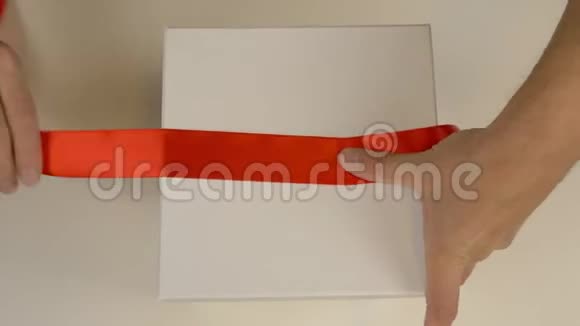 动作快包装白色礼盒白人男子的手包装礼品盒男人的手在白色的周围系一条红丝带视频的预览图