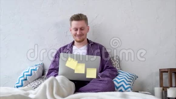 快乐的男人躺在卧室里用笔记本电脑看电影视频的预览图