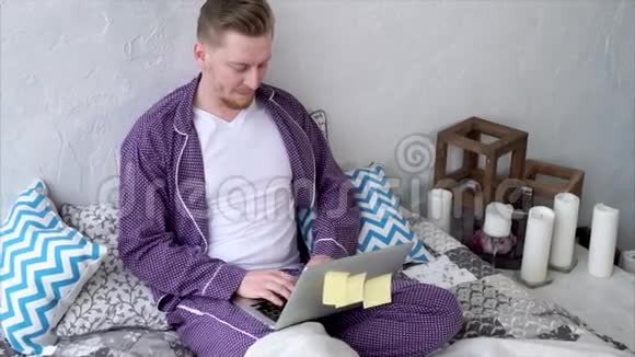 穿睡衣的快乐成年男人和女友一起写笔记本电脑视频的预览图