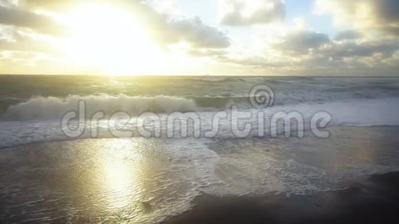 慢慢地波浪在夕阳下撞向岸边视频的预览图