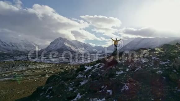 在雪山空中飞行史诗般的胜利中年轻的徒步旅行者伸出双臂成功地在日落时摆出姿势视频的预览图