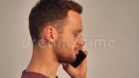 红发男子正侧身站着在电话里聊天背景是白色的视频的预览图
