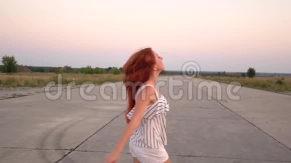 快乐的红发女人旋转她的头发在风中飘扬视频的预览图
