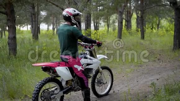 一个戴着防护头盔和特殊制服的运动员骑着越野摩托车在大自然中的森林中视频的预览图