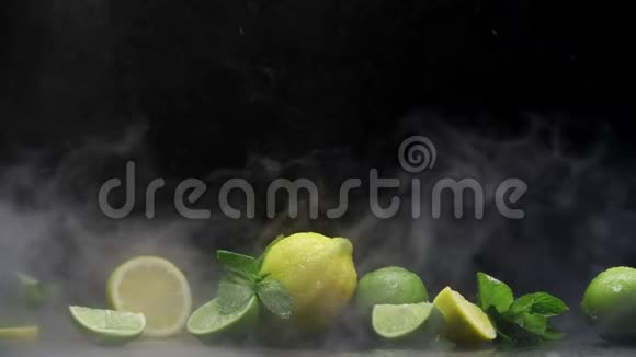 新鲜柠檬和石灰在冷水喷雾和黑底冰雾下切割视频的预览图