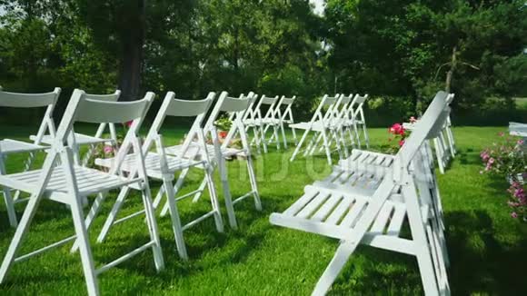 阶梯射击绿色草坪与一排排白色木椅举行婚礼的地点视频的预览图