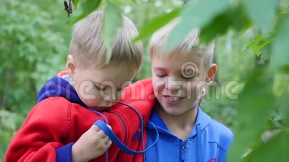男孩拥抱弟弟把他抱在怀里夏季公园视频的预览图
