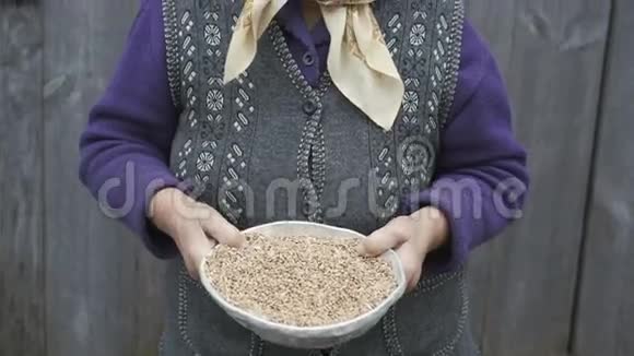 一位笑容可掬的老妇人手里拿着一碗麦粒麦粒的画像视频的预览图
