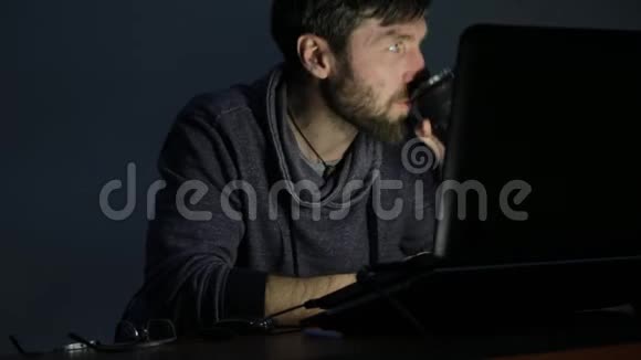 大胡子在笔记本电脑前吃三明治工作起来开始心烦意乱视频的预览图
