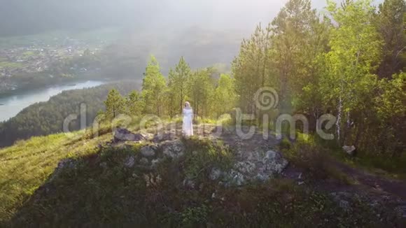 一个穿着白色衣服的女孩站在山上从上面可以看到美丽的景色视频的预览图