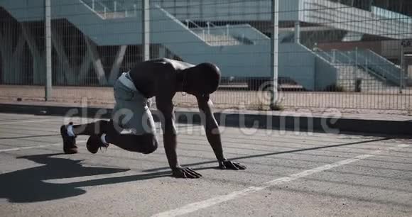 美国黑人运动员在体育场附近的街道上快速地在前面的木板上弯曲双腿健身健康视频的预览图