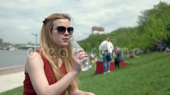 戴墨镜的年轻女子夏天喝塑料瓶里的水视频的预览图