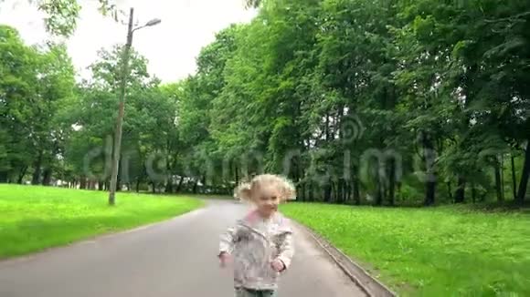 活跃的金发女孩辫子在镜头前穿过公园路视频的预览图