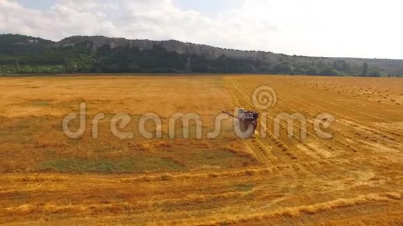 联合收割机收获小麦在远处的群山和一捆干草中视频的预览图