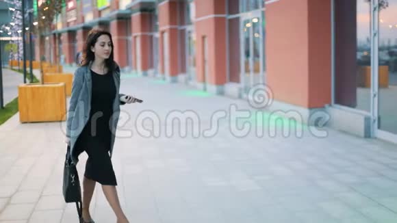 年轻漂亮的女商人脖子上有纹身穿着严格的灰色夹克和黑色连衣裙走在街上视频的预览图
