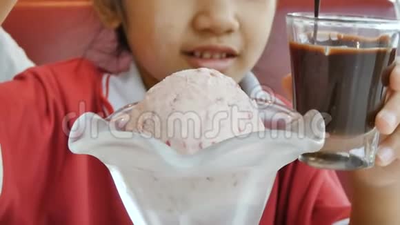 用汤匙把液体巧克力倒入冰淇淋的勺上特写拍摄的亚洲小女孩视频的预览图