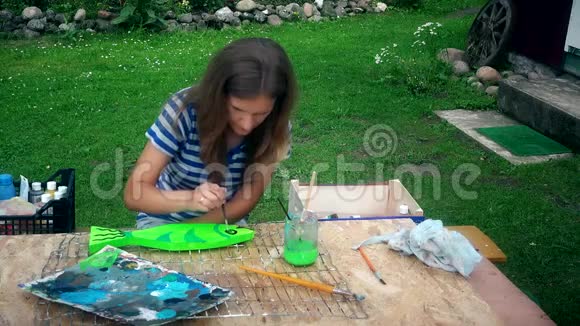 女青年画家在院子里的木桌上画鱼装饰视频的预览图