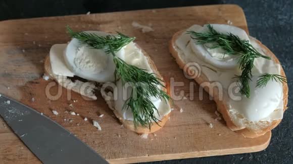 黑色背景的木板上有面包黄油鸡蛋和的特写三明治做三明治视频的预览图