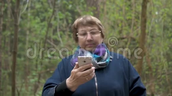 一位年长的美女看着一部智能手机带来美丽梳头调整衣服去散步视频的预览图