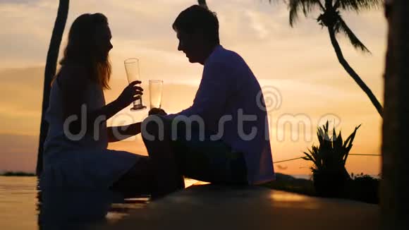 男人和女人在海滩日落时喝酒两人浪漫之夜视频的预览图