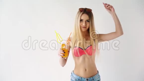 穿着泳衣喝着彩色饮料在白色背景下跳舞的女孩视频的预览图