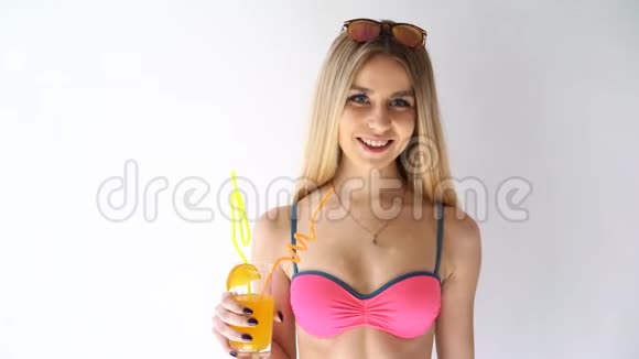 穿着泳衣喝着彩色饮料在白色背景下跳舞的女孩视频的预览图