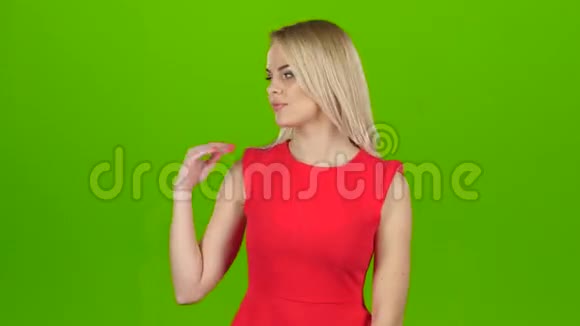 在绿色屏幕背景下穿红色衣服的女士展示了她的手视频的预览图